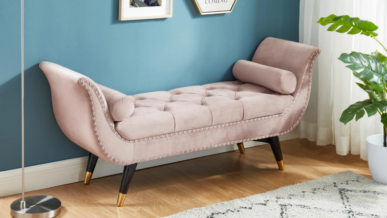 A pink velvet settee on display against a wall.