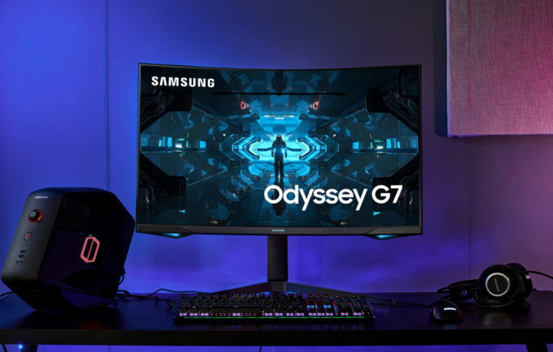 A monitor sitting on a desk near a keyboard, mouse, headset, and tower PC; the Odyssey G7, one of the best 32-inch gaming monitors