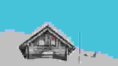 在冬季景观前的一个被雪覆盖的小屋的蓝色复选标记审查的背景。