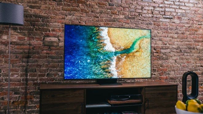 Flat screen TV in front of brick wall indoors.