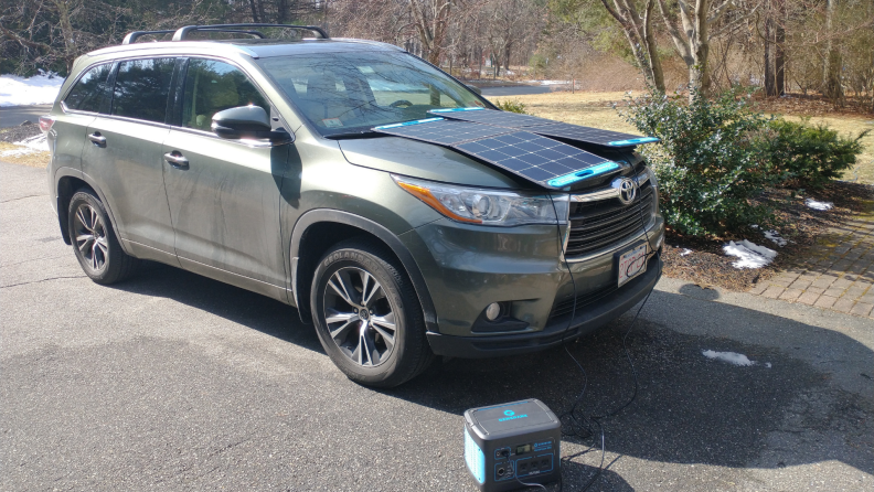 Solar panel being charged on hood of SUV on a sunny day.