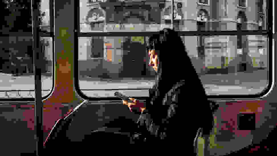 A passenger on public transit uses a smartphone.