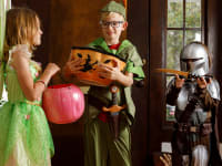 Three kids wearing Halloween costumes: Tinker Bell, Peter Pan, and the Mandalorian