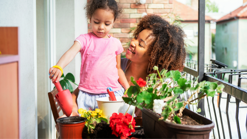mother and daughter watering plants in containers