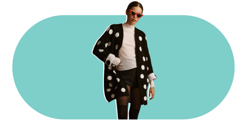 A model wearing a black cardigan with white polka dots.