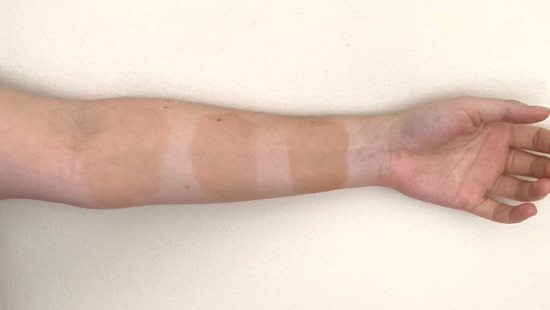 The author's arm with swatches of the three top self-tanners.