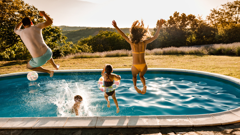 Family of four jumping into a swimming pool outdoors
