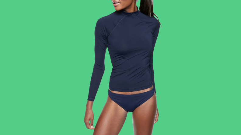 Black woman wearing navy surf shirt on green background.