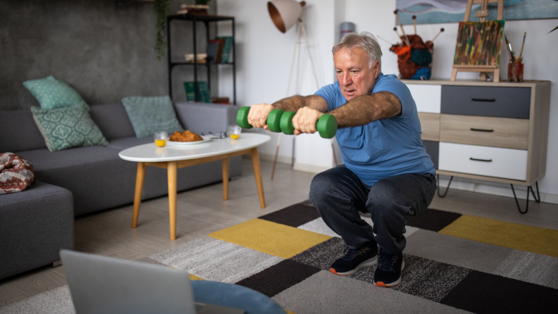 A person squats with weights at home.