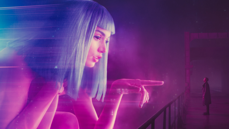 A hologram advertisement, played by Ana de Armas, towers over Ryan Gosling in Blade Runner 2049.
