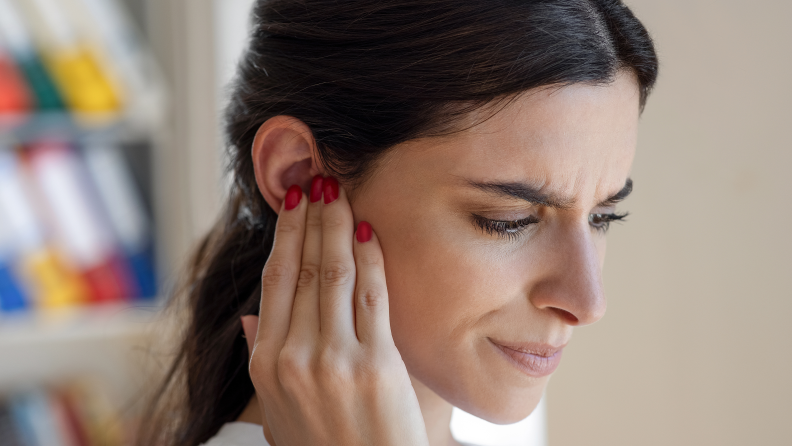 A woman pressing a hand to her ear