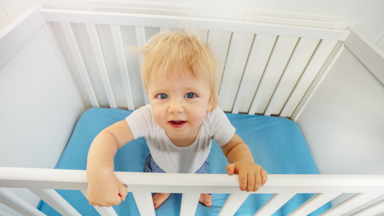A child looks up from their crib at the camera