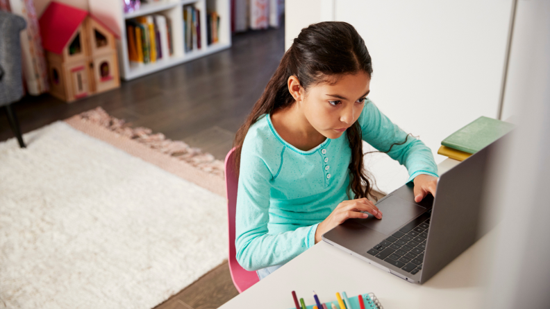 Small child using laptop computer at desk indoors.