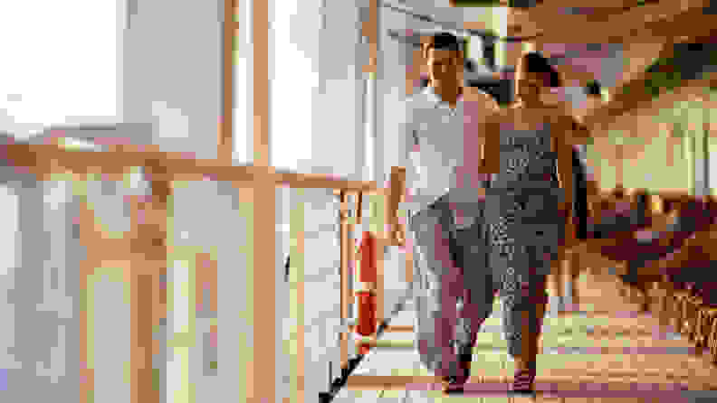 A man and woman walking arm in arm on a cruise ship.