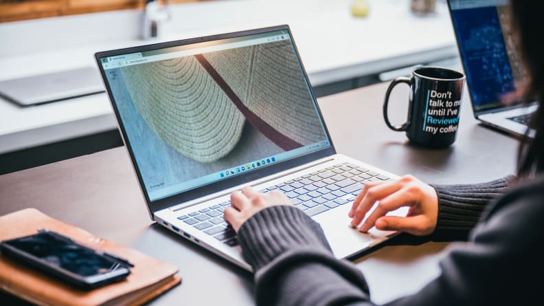 The Galaxy Book being used on a desk, with a cup of coffee and a cell phone next to it.