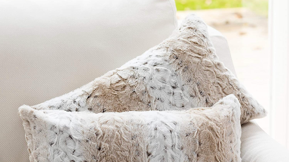 Close-up of two fur-textured tan throw pillows on a couch.