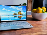 An HP Spectre laptop sitting next to a bowl of fake fruit.