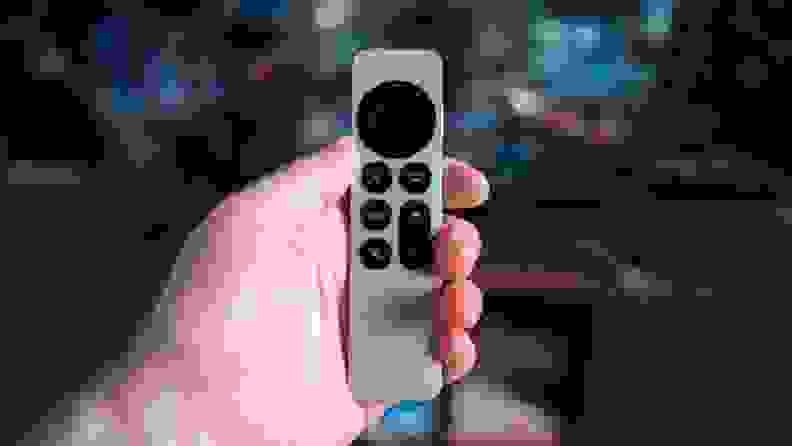 The Apple TV 4K remote in someone's hand in front of a television.