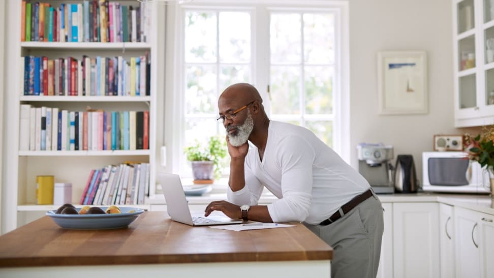 Person standing at butcher block kitchen island while looking at computer screen