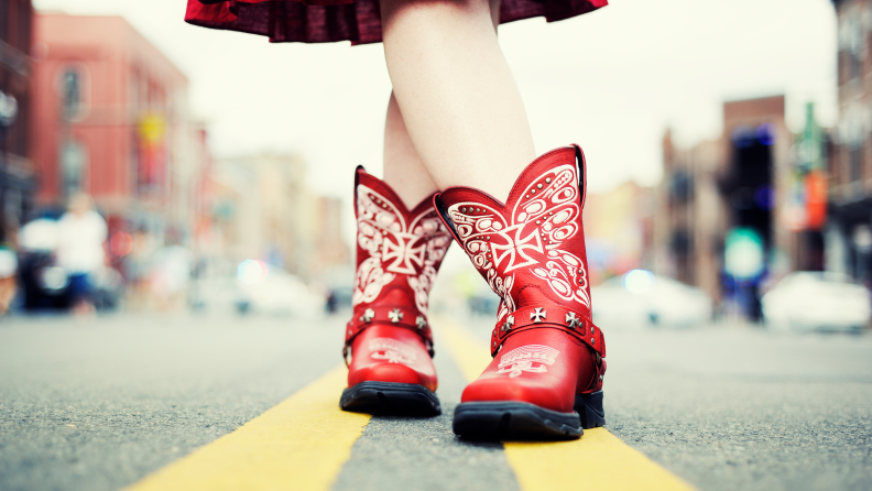 Close-up of someone wearing red cowboy boots with a red dress.