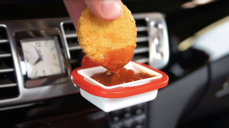 Hand dipping nugget into ketchup dip clip on car vent