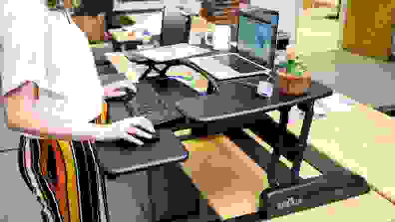 Close-up of a person working on a laptop at the VariDesk Pro Plus standing desk.