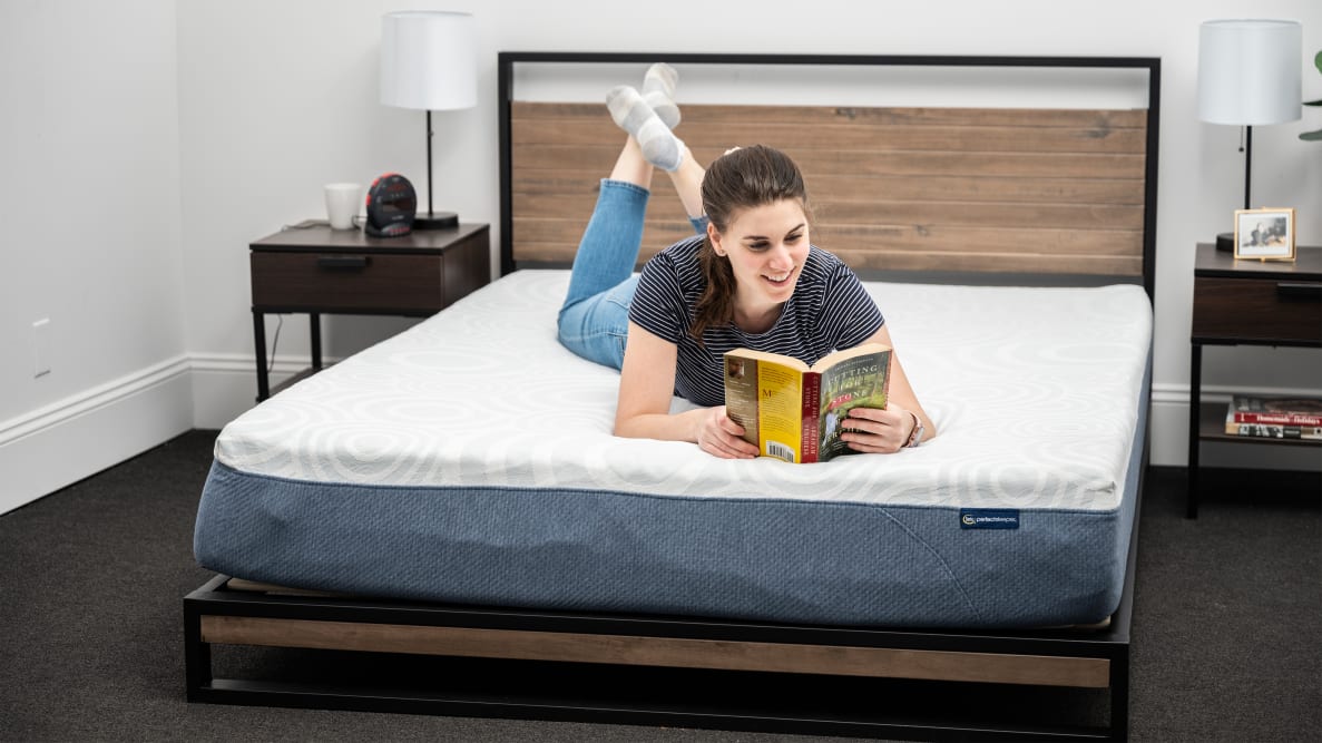 woman lying on serta mattress reading a book with a yellow cover