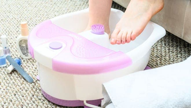 A person sits with their feet in a foot spa