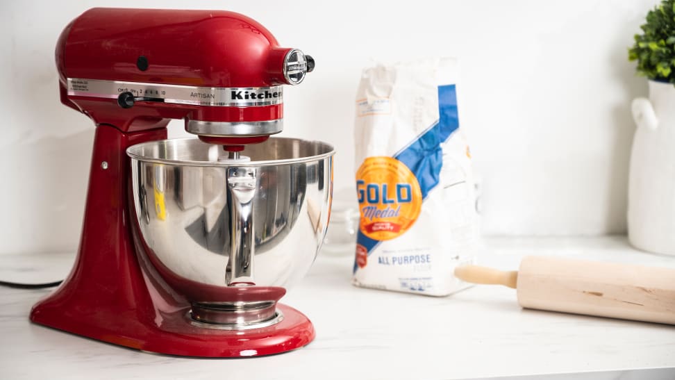 A red KitchenAid stand mixer on a countertop with baking accessories.