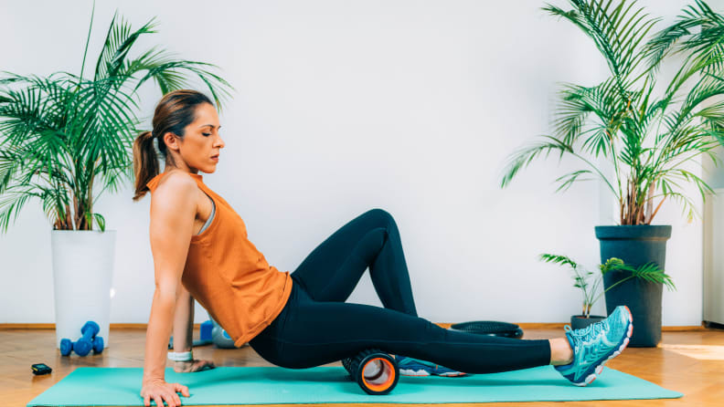 A woman foam rolling her hamstring.