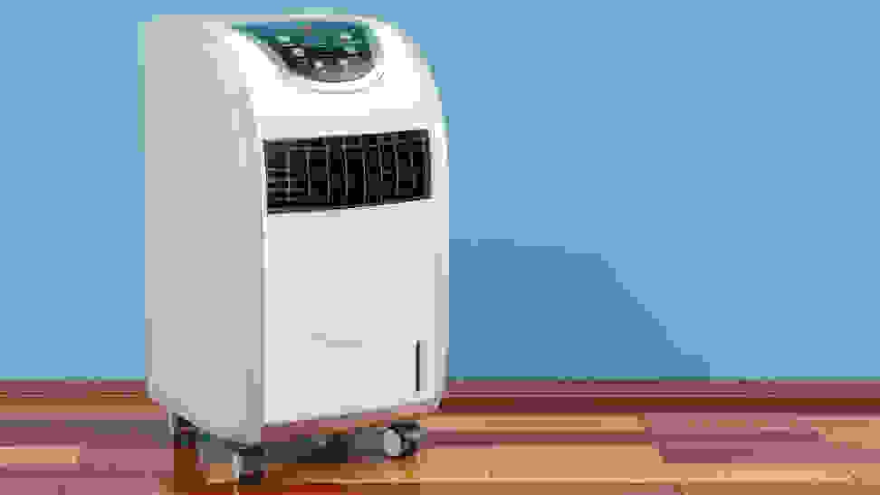 A large white portable air conditioner with wheels stands on a wood floor.
