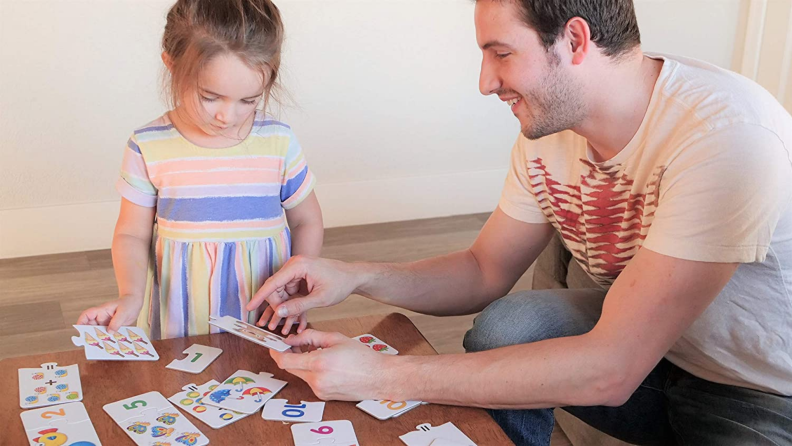 A child assembles a puzzle with the help of their parent.