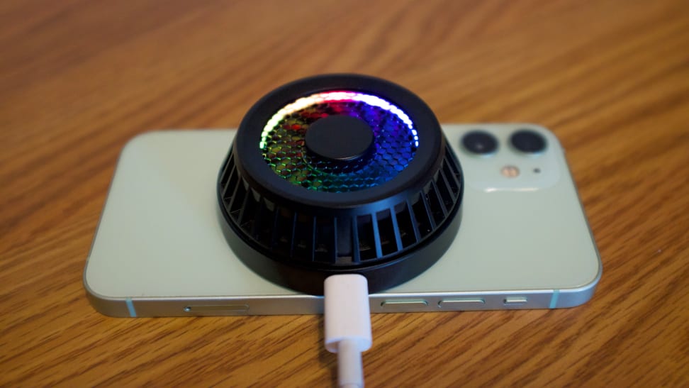 Razer's Phone Cooler Chroma (Magsafe edition) attached to an iPhone 12 Mini and tethered to a USB-C cable, with a multi-color LED glowing around the inside of the fan.