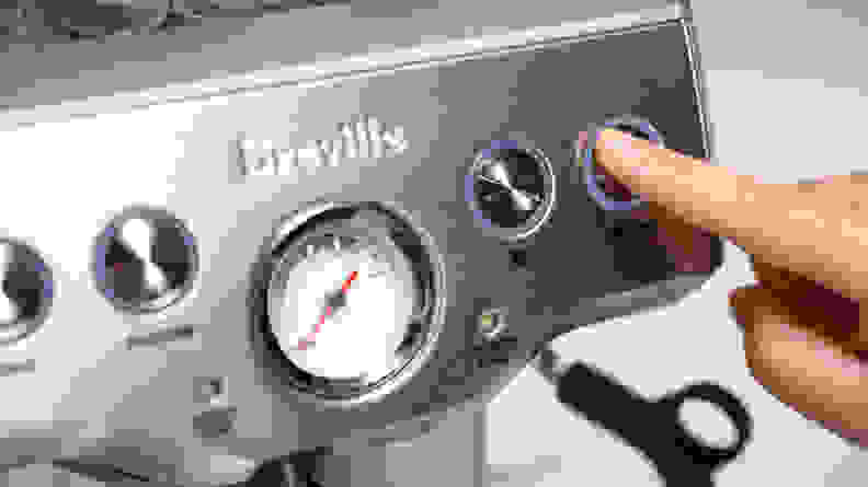 Finger pressing button on Breville Infuser machine.