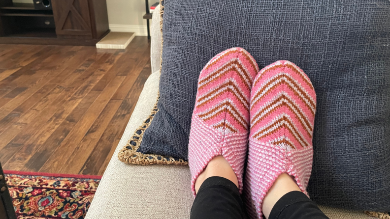 Person wearing pink Bombas Slippers on a couch.