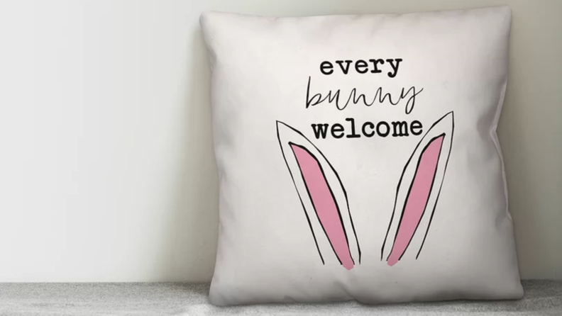 White pillow with pink bunny ears and a caption reading Every Bunny Welcome