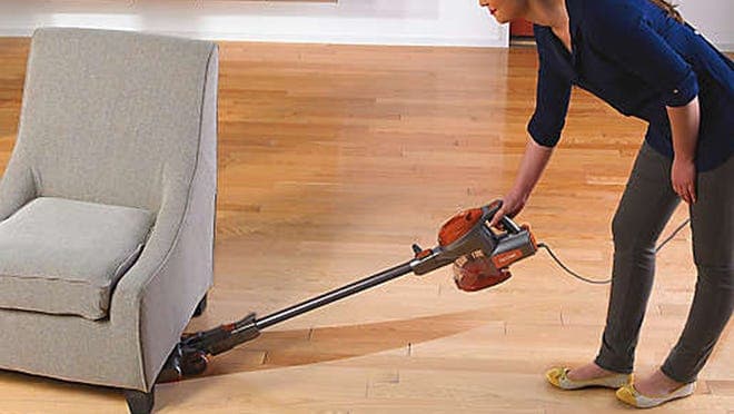 Person using vacuum to clean floor in home.