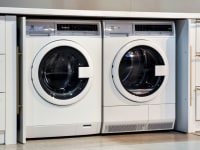 A compact washer and dryer underneath a countertop, in a cutout in the surrounding cabinetry.
