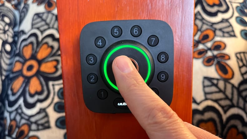 Person using finger to engage with touch button on smart lock.
