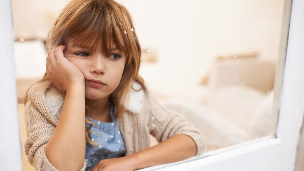 Bored little girl looking out a window.