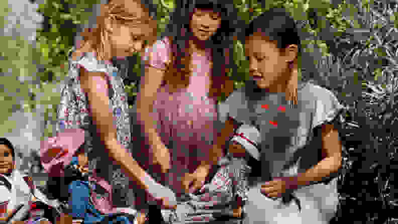 Three girls having a tea party with their American Girl dolls