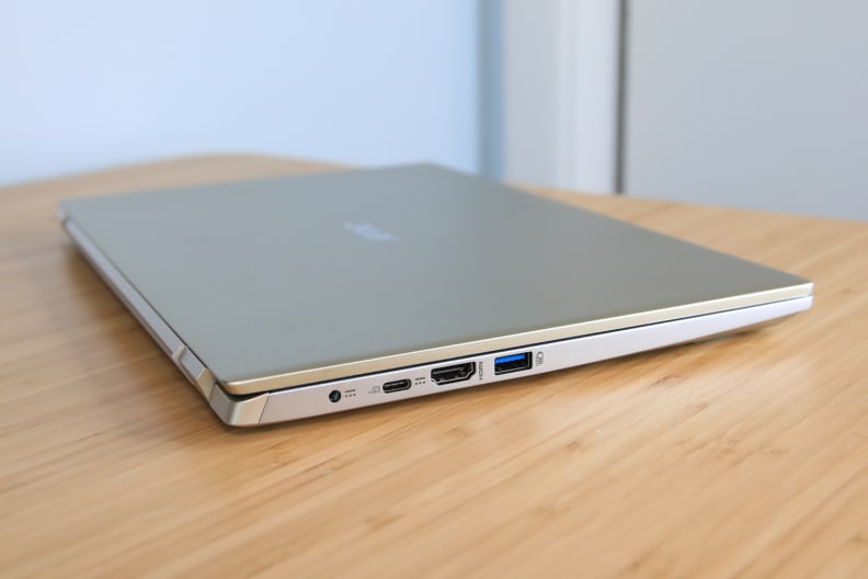 A side view of a closed laptop on top of a light brown wooden surface.