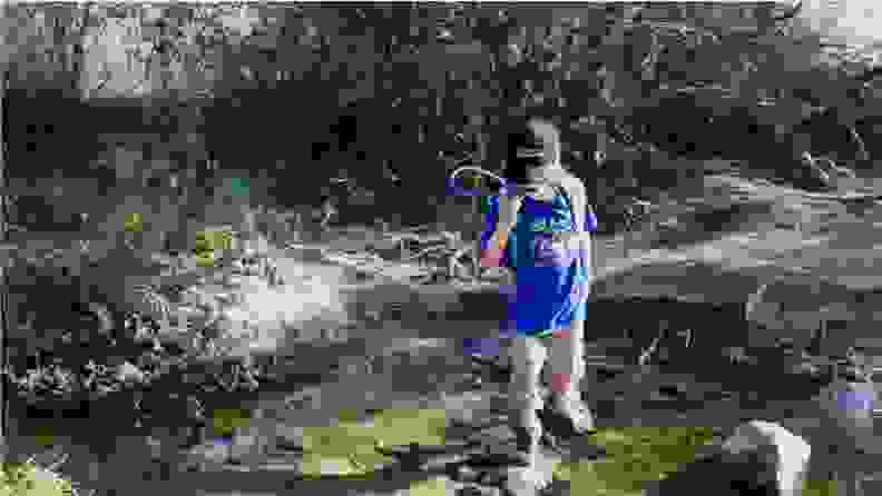 A young boy crossing a stream on a hiking trip.