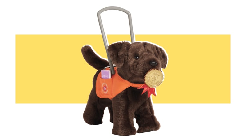 An American Girl brown Service Dog with a handle and a bandana on a yellow background.