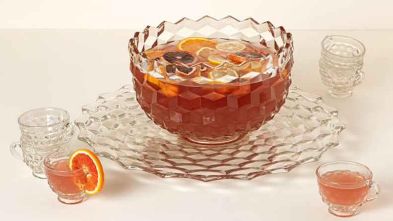 A punch bowl surrounded by matching punch cups.