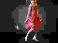 A young girl wearing a pink sundress and dancing with a wand