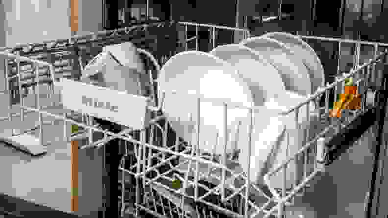 A few mugs and bowls sit in the middle rack of the dishwasher.