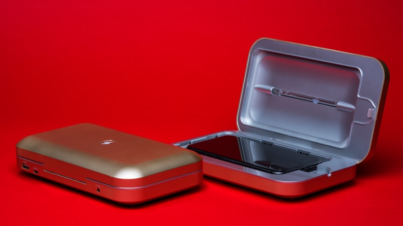 A cell phone in a PhoneSoap sanitizer on a red background