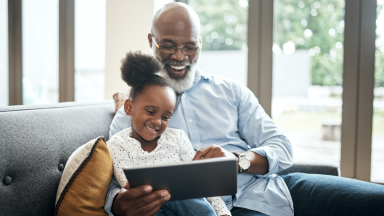 Grandfather and child sitting on a couch with a tablet