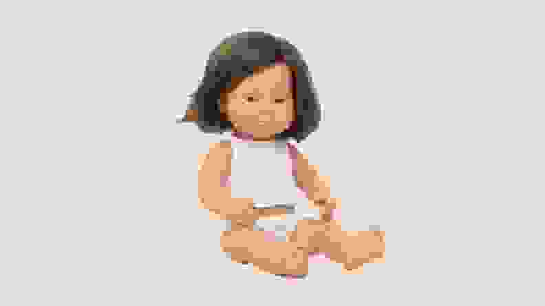 A Caucasian Miniland girl doll product shot on a colorful background